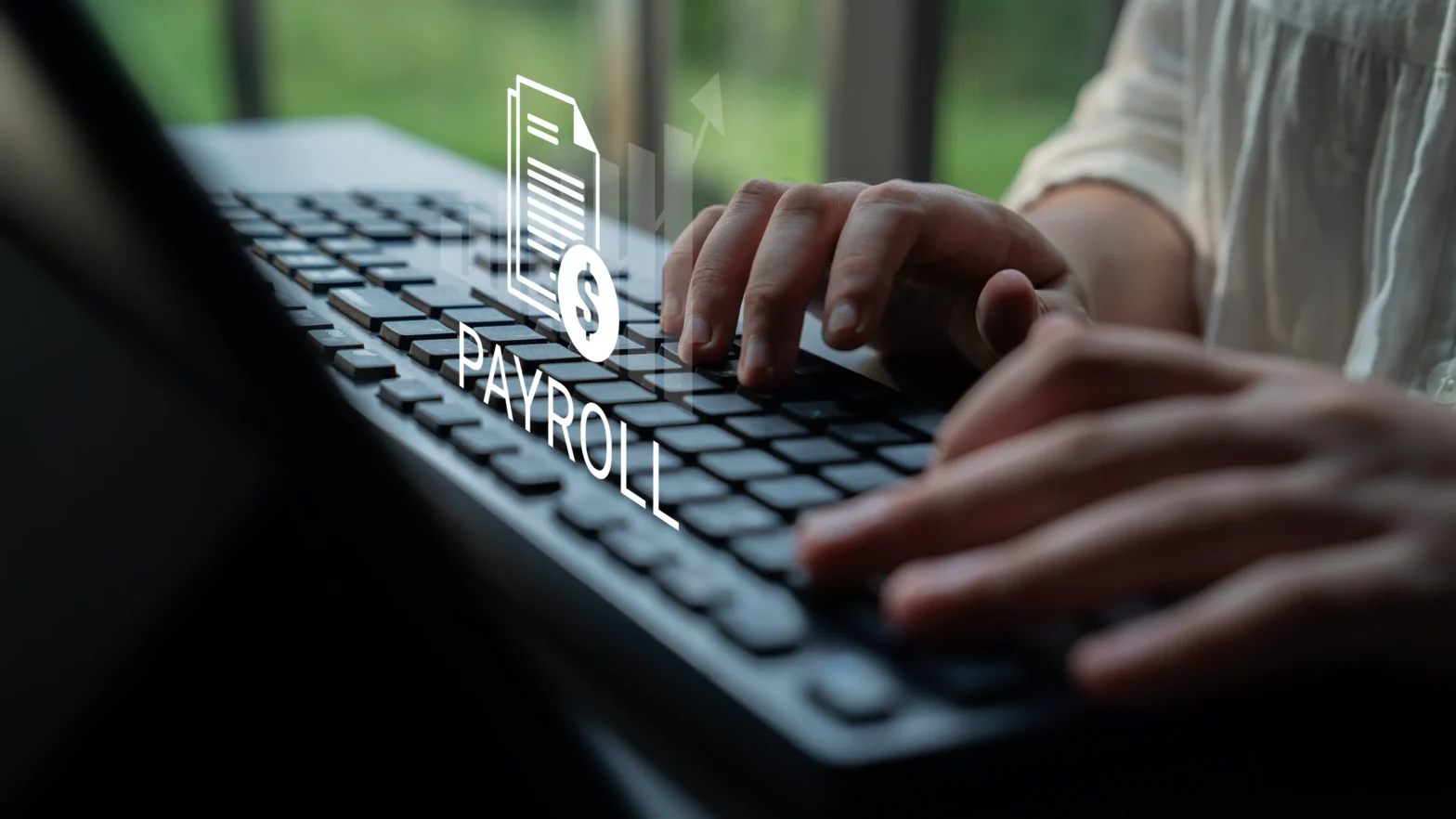 Hands typing on a computer keyboard with digital payroll icon overlay.